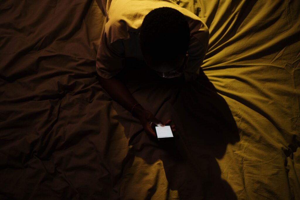 Phone glowing in a dark room late at night — revenge bedtime procrastination